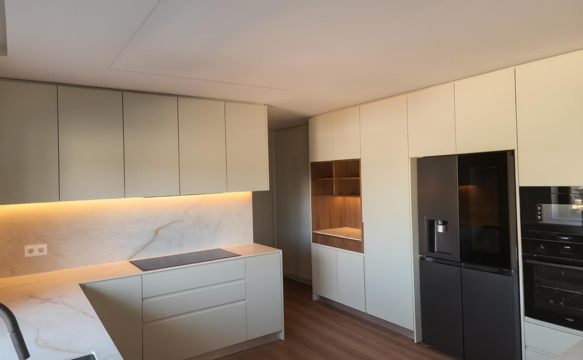 Cozinha lacada com revestimento em mármore e eletrodomésticos encastrados