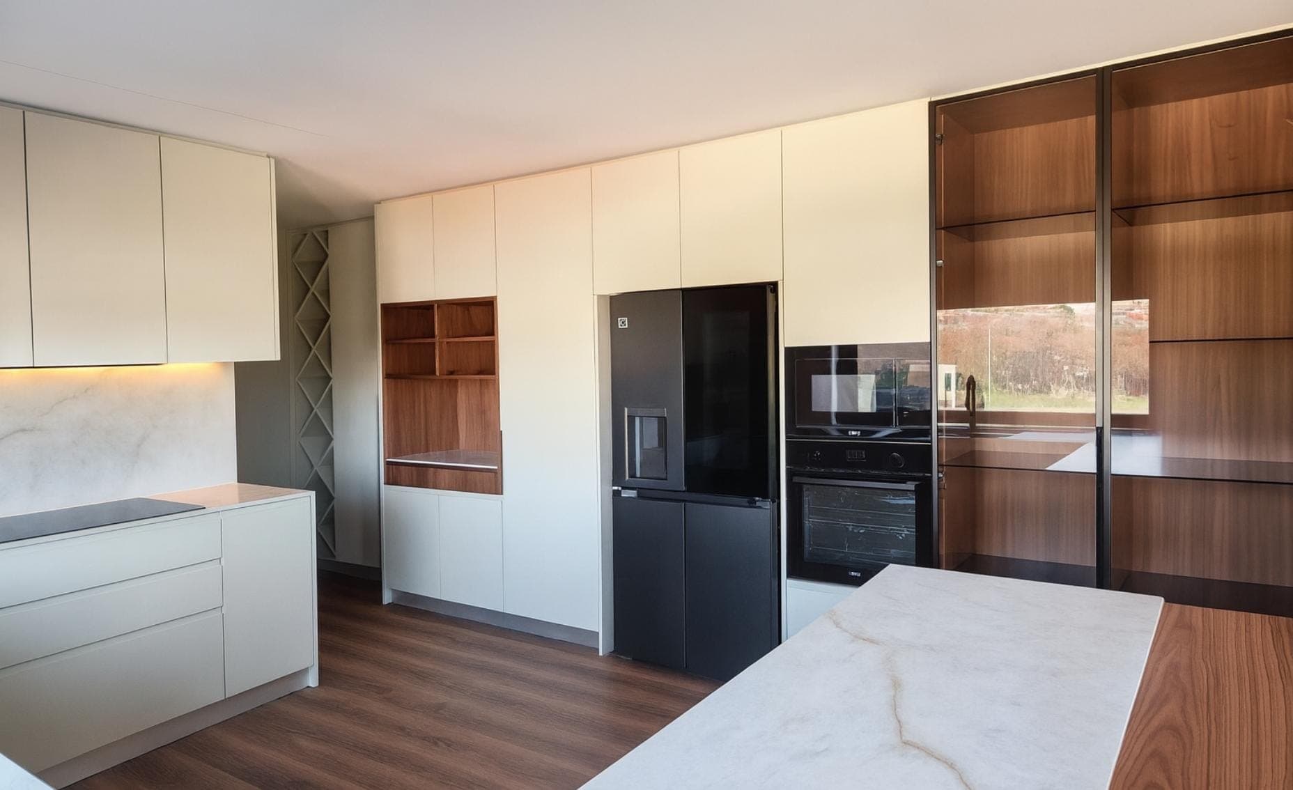 Cozinha com ilha em mármore e nogueira, armário-vitrine e frigorífico americano