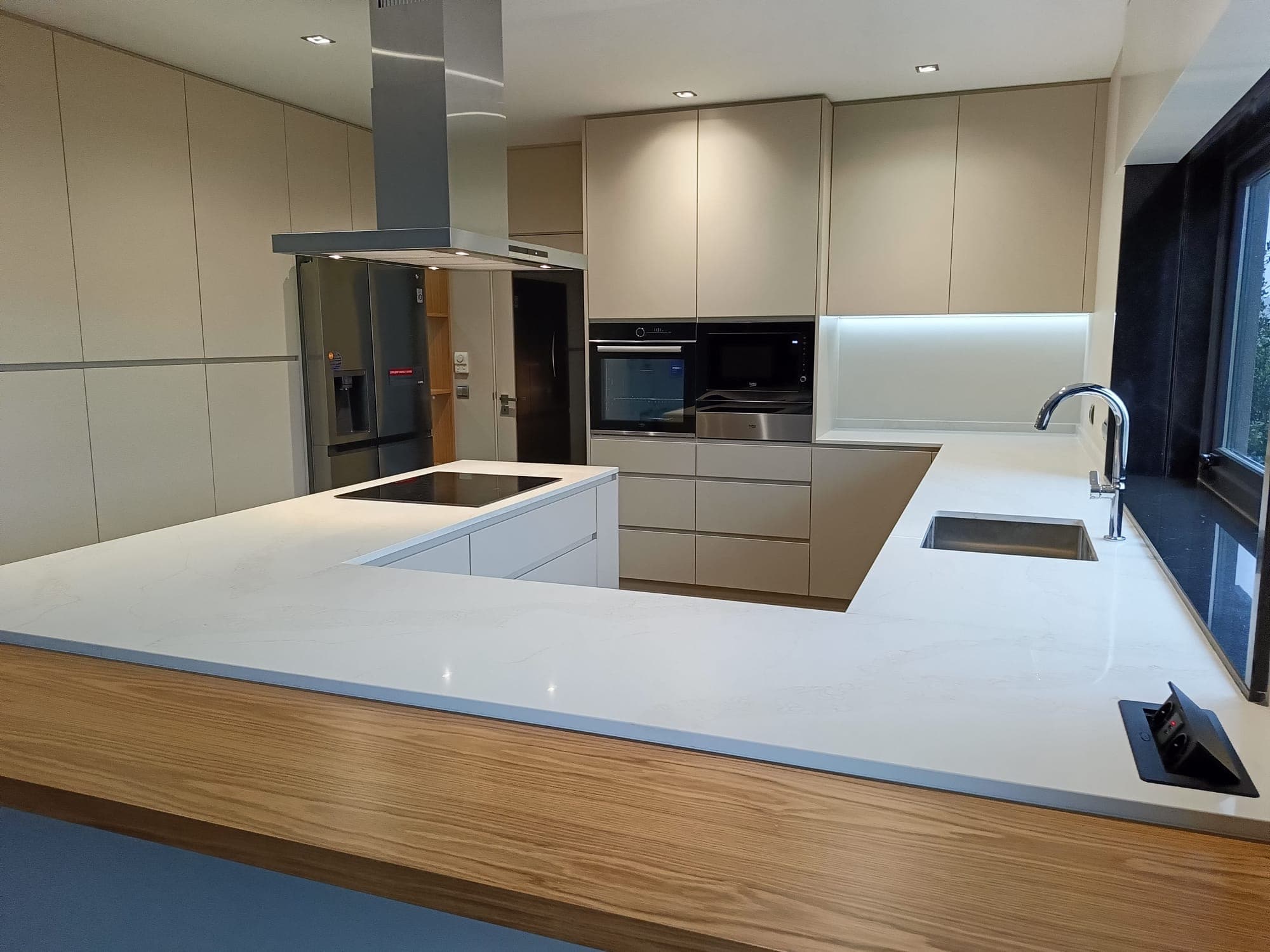 Cozinha em U contemporânea com bancadas em quartzo branco e exaustor de ilha